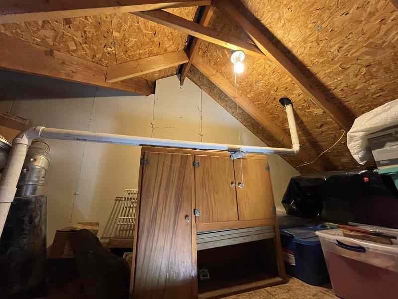 Responded to service call regarding potential HVAC exhaust pipe issue following recent roof replacement. Upon inspection of attic space, located and examined white PVC exhaust pipe penetration through roof decking where roofers had identified concerns about loose fitting that could allow water intrusion during storms. Assessed pipe mounting, support straps, and roof penetration seal. Verified proper securing of exhaust pipe to structural members using appropriate hangers and confirmed adequate clearance from combustible materials per code requirements. Inspected surrounding area for any existing water damage or staining that would indicate previous leakage. Examined condition of pipe connections and joints in accessible attic area. System currently operational with no immediate safety concerns identified. Documented conditions with photographs for reference.