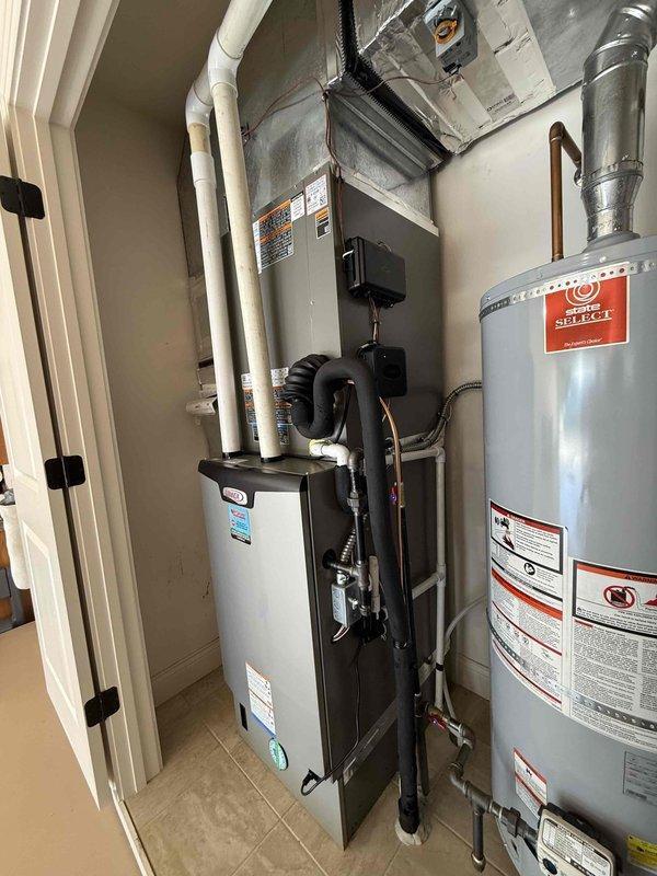 # Complete HVAC System Installation

Installed a complete 5-ton, 18 SEER, 99% AFUE GREEN heating and cooling system with PureAir air purification and a 2-zone automatic damper system. The installation included indoor air handler with curved black ducting, white PVC condensate drainage system, and outdoor condensing unit with proper refrigerant charging verified using digital manifold gauges. System was evacuated, charged to manufacturer specifications, and tested for proper operation across both zones with all safety controls and air quality components functioning as designed.