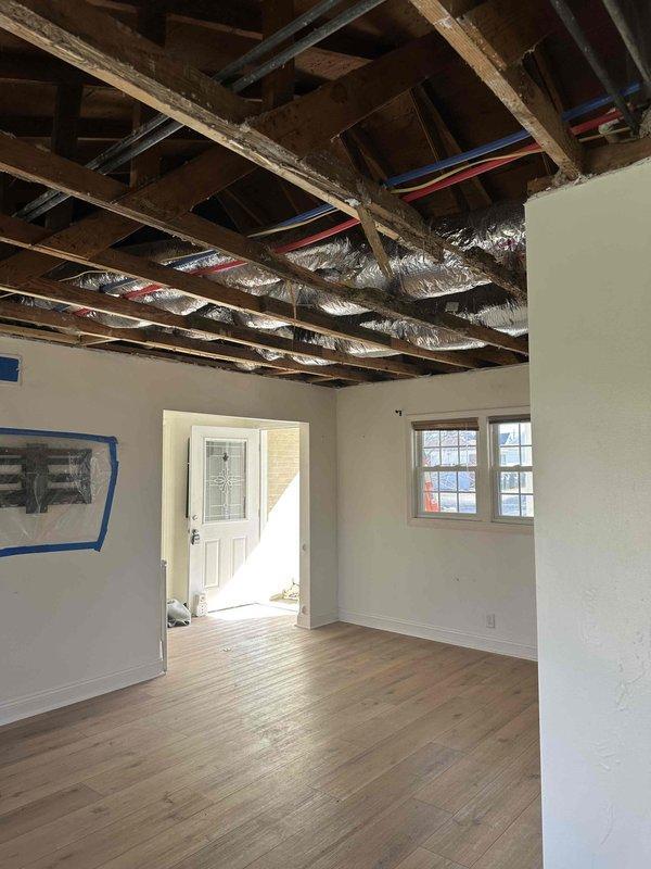Completed installation of new ductwork in renovation area, including proper insulation of silver ducts running between exposed ceiling joists. System connects to existing A.O. Smith ProLine Commercial Grade water heater with appropriate ventilation piping secured with metal tape at joints.
