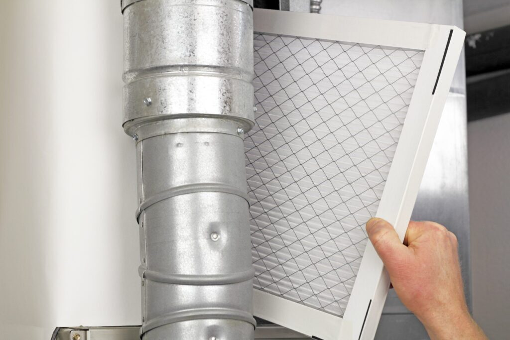 Person replacing disposable air filter in residential air furnace as part of regular duct cleaning maintenance