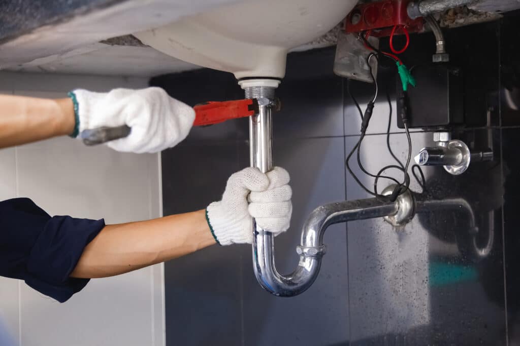 Plumber fixing white sink pipe with adjustable wrench 