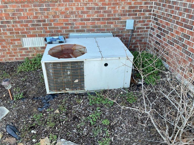 Conducted comprehensive evaluation of aging outdoor HVAC system showing significant deterioration including extensive rust on fan assembly, weathered housing, and corrosion on adjacent components. Unit positioned against brick exterior wall exhibits end-of-life indicators and requires full system replacement as discussed with customer who is interested in the tankless water heater promotion with complete system installation.