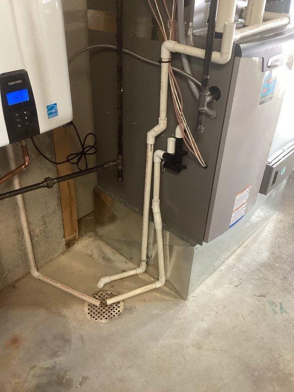 Conducted follow-up site visit to inspect and document existing HVAC and plumbing installations in mechanical room. Photographed furnace/air handler unit, water heater, PVC drainage piping, copper refrigerant lines, condensate pump assembly, and floor drain configuration to verify proper installation and system operation. All equipment observed in normal working condition with standard connections and compliance labeling intact.