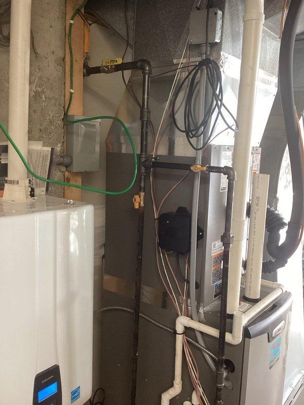 Conducted follow-up site visit to inspect and document existing HVAC and plumbing installations in mechanical room. Photographed furnace/air handler unit, water heater, PVC drainage piping, copper refrigerant lines, condensate pump assembly, and floor drain configuration to verify proper installation and system operation. All equipment observed in normal working condition with standard connections and compliance labeling intact.