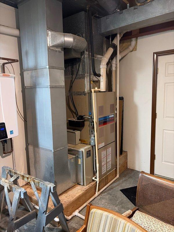 Responded to a second opinion service call for an older HVAC system, approximately 1997 model, where a previous contractor indicated the thermostat was wired incorrectly. Performed diagnostic assessment of the furnace and air distribution system located in the basement utility area, inspecting thermostat wiring, furnace operation, and ductwork configuration. Documented existing equipment conditions including the furnace unit, metallic ductwork routing, flexible ducting connections, and overall system installation for evaluation and recommendation purposes.