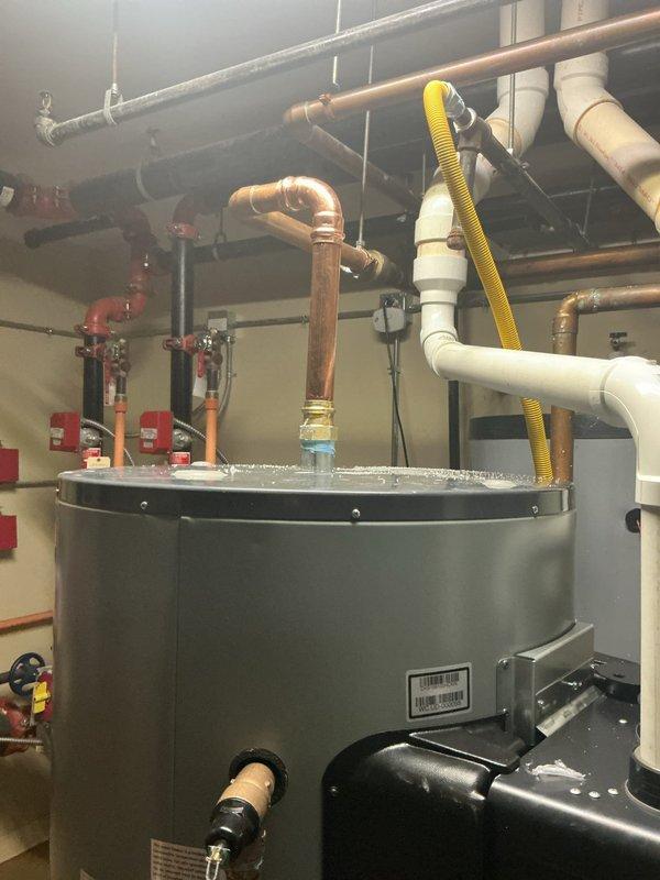 Completed multi-day installation of dual Rinnai 119-gallon gas water heaters with on-demand heating capabilities in commercial mechanical room. Removed existing leaking 120-gallon storage tank and installed new TJV120M replacement unit. Reconnected previously warranty-replaced Rinnai unit to new storage tank system. Installed all necessary copper piping, PVC connections, gas lines, pressure relief valves, and circulation components to integrate both water heaters into existing plumbing infrastructure. Repaired visible leaks throughout water heater plumbing system including connections, joints, and supply lines. Configured dual-unit system with proper venting, combustion air supply, and safety controls. Tested all connections for leaks, verified proper gas pressure, confirmed operational functionality of on-demand heating systems, and ensured compliance with manufacturer specifications and local plumbing codes.