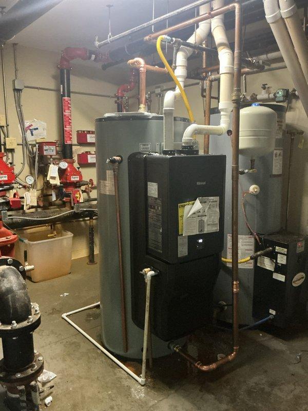 Completed multi-day installation of dual Rinnai 119-gallon gas water heaters with on-demand heating capabilities in commercial mechanical room. Removed existing leaking 120-gallon storage tank and installed new TJV120M replacement unit. Reconnected previously warranty-replaced Rinnai unit to new storage tank system. Installed all necessary copper piping, PVC connections, gas lines, pressure relief valves, and circulation components to integrate both water heaters into existing plumbing infrastructure. Repaired visible leaks throughout water heater plumbing system including connections, joints, and supply lines. Configured dual-unit system with proper venting, combustion air supply, and safety controls. Tested all connections for leaks, verified proper gas pressure, confirmed operational functionality of on-demand heating systems, and ensured compliance with manufacturer specifications and local plumbing codes.
