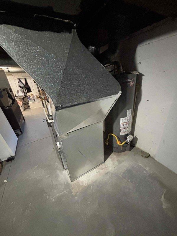 Completed full HVAC system installation including new air handler unit positioned in utility room corner with black flexible ductwork connections routed to ceiling plenum. Installation included complete duct runs with reflective insulation wrapping applied to exposed ductwork in conditioned living spaces to maximize thermal efficiency and minimize heat loss/gain. System commissioned and tested for proper airflow and operation upon completion.