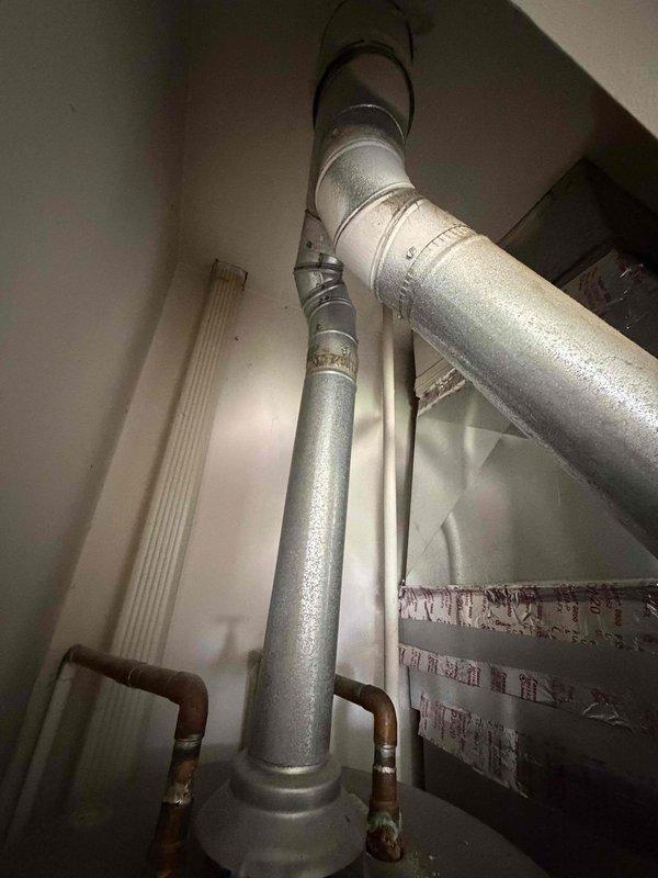 Responded to service call regarding damaged HVAC flue pipe identified during home inspection. Upon arrival, inspected the vent pipe system in the mechanical room and confirmed significant rust and corrosion on the metal flue pipe and connecting sections. Documented the deteriorated condition of the ductwork, noting discoloration, oxidation on copper connections, and compromised integrity of the venting system. Provided same-day pricing estimate for complete flue pipe replacement to address safety concerns and bring system into compliance with proper venting standards.