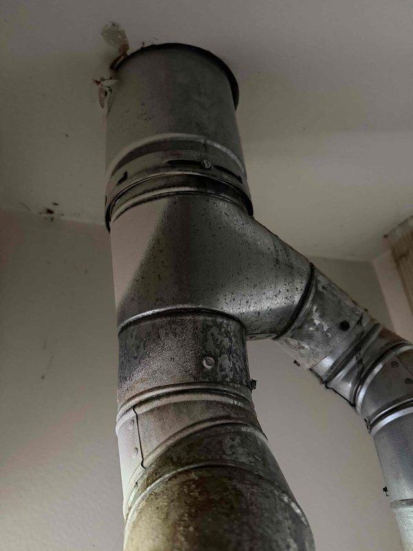 Responded to service call regarding damaged HVAC flue pipe identified during home inspection. Upon arrival, inspected the vent pipe system in the mechanical room and confirmed significant rust and corrosion on the metal flue pipe and connecting sections. Documented the deteriorated condition of the ductwork, noting discoloration, oxidation on copper connections, and compromised integrity of the venting system. Provided same-day pricing estimate for complete flue pipe replacement to address safety concerns and bring system into compliance with proper venting standards.