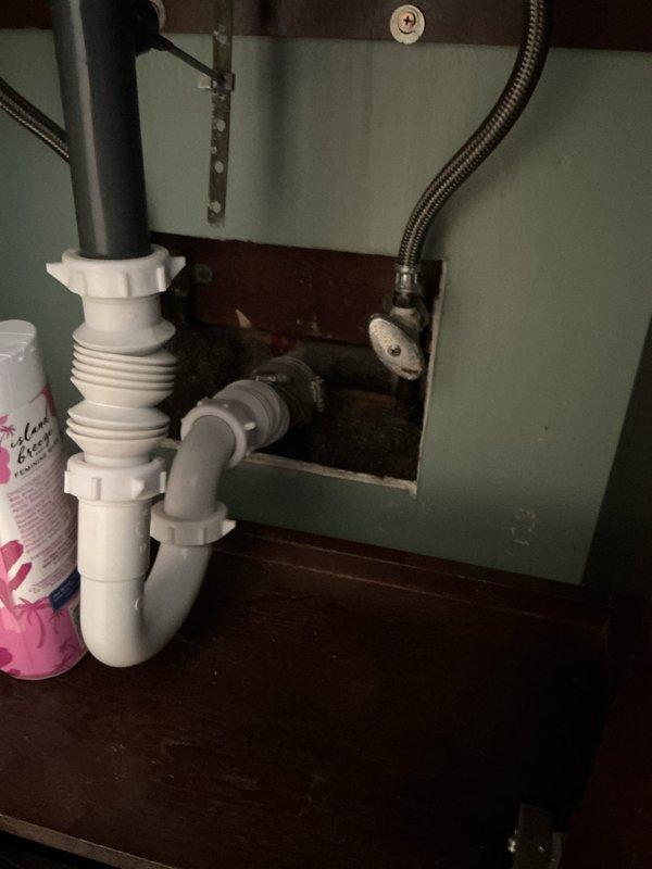 Responded to water leak in yard of 70-year-old residential property where leak had been active for one to two weeks. Inspected under-sink plumbing connections including PVC P-trap assembly, tailpiece, and flexible braided stainless steel supply lines to identify potential source points. Documented existing plumbing configuration with white PVC drain components and shut-off valve connections for service record purposes.