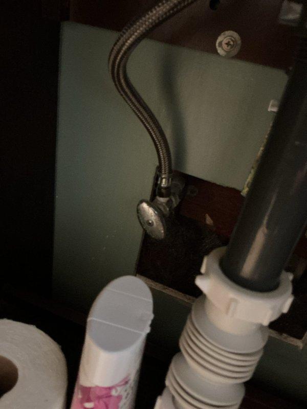 Responded to water leak in yard of 70-year-old residential property where leak had been active for one to two weeks. Inspected under-sink plumbing connections including PVC P-trap assembly, tailpiece, and flexible braided stainless steel supply lines to identify potential source points. Documented existing plumbing configuration with white PVC drain components and shut-off valve connections for service record purposes.