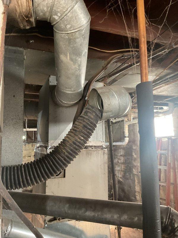 Conducted comprehensive ductwork assessment in unfinished basement utility space to evaluate existing HVAC distribution system and provide estimate for replacement. Documented current ductwork configuration including large cylindrical insulated supply trunk, metallic flex connections, and rigid metal branch ducts running through exposed floor joists. Identified aged galvanized metal ductwork with flexible ribbed connections showing signs of deterioration, dust accumulation, and potential air leakage points at seams and joints. Evaluated structural clearances, existing routing pathways, and accessibility for new ductwork installation throughout the mechanical space.